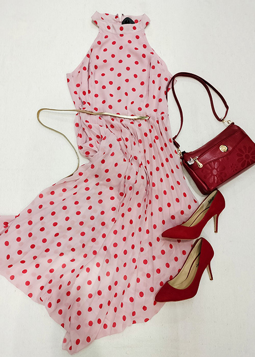 Flatlay of pink and red polka-dot dress with red heels and red hand bag